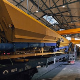 Train béton ferroviaire en maintenance dans un atelier industriel avec équipements hydrauliques et mécaniques en cours de rénovation