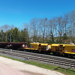 Rame de ballastage automatisée Novium circulant sur voie ferrée avec wagons de ballast SNCF pour opérations de maintenance ferroviaire