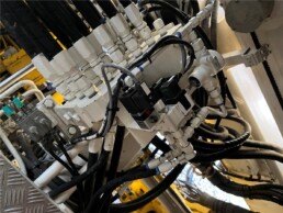 Bloc hydraulique industriel avec flexibles et connectiques lors d’une opération de maintenance.