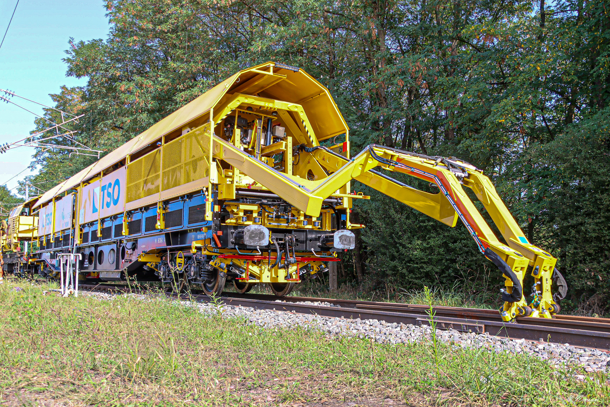 Engin MANTIS de maintenance ferroviaire retirant des débris sur la voie